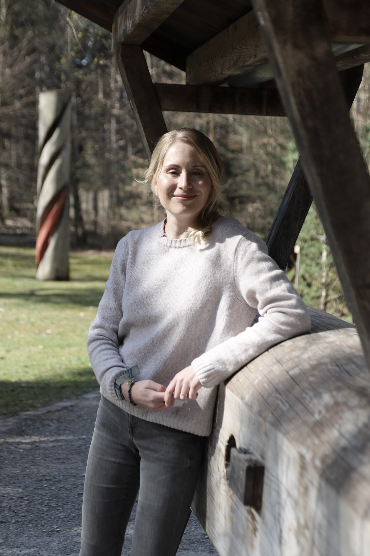 Nathalie Koschik von Body Mind Memories lehnt an einem Baumstamm und blickt lächelnd in die Kamera