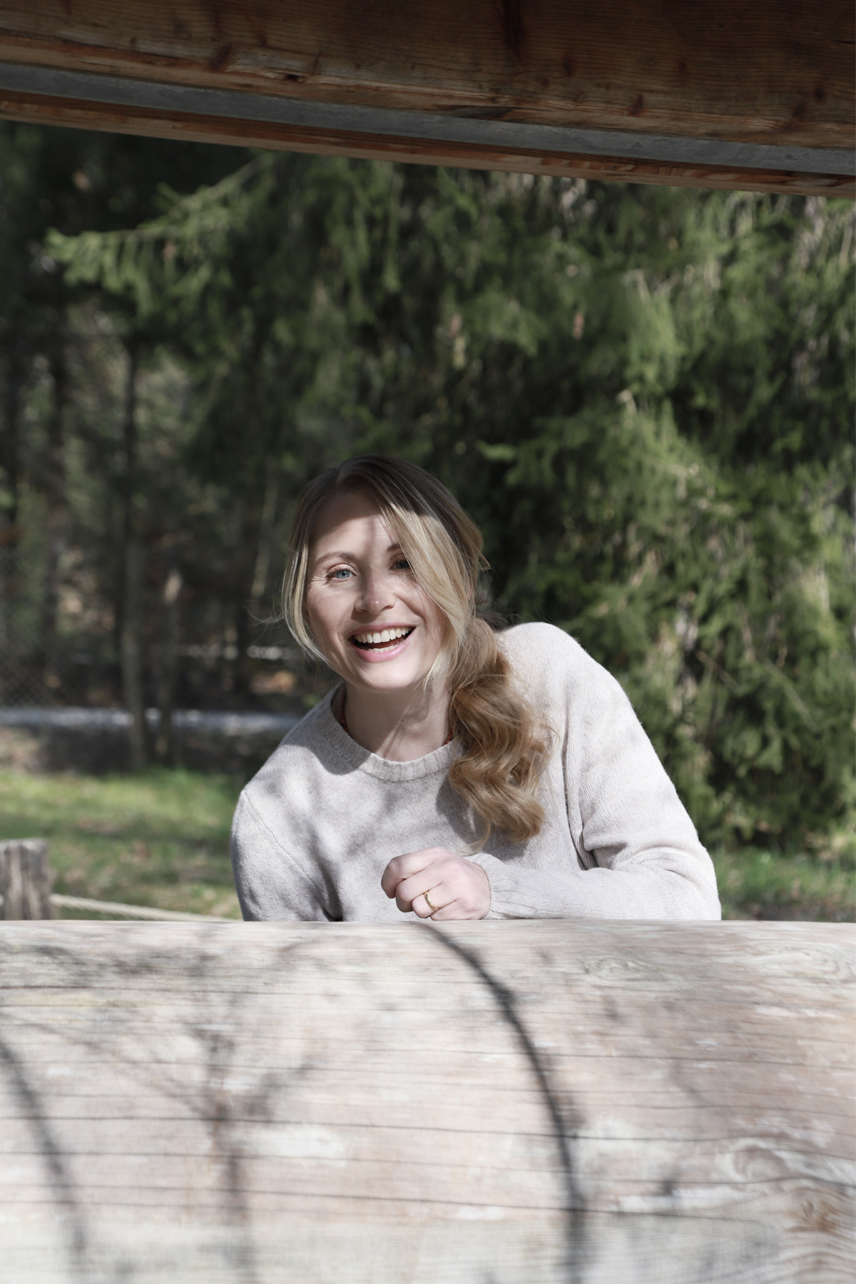 Nathalie Koschik von Body Mind Memories steht hinter einem Baumstamm und blickt lächelnd in die Kamera